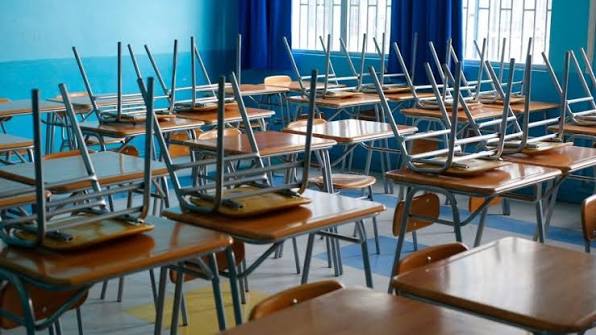 Sala de clases con sillas sobre las mesas.