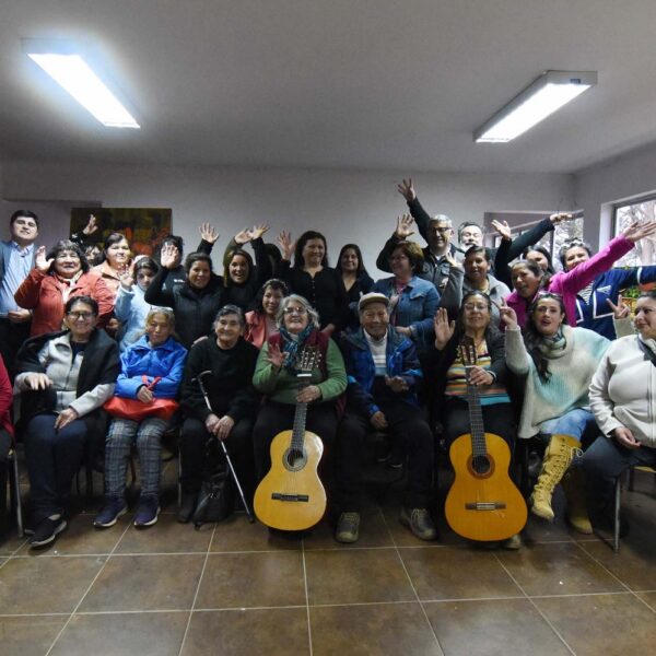 Vecinas, vecinos y artistas posan junto a dos guitarras durante una Mateada Cultural en Canelillo.
