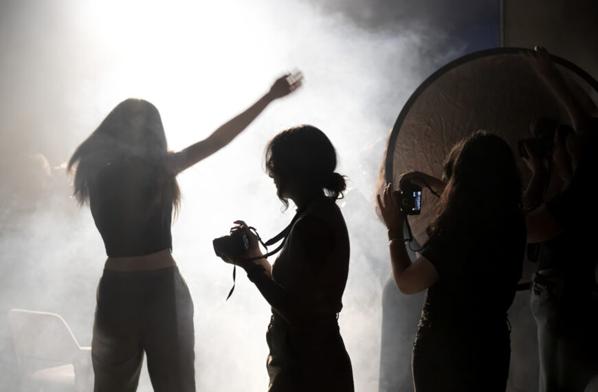 Mujeres fotografían una sesión en un estudio iluminado a contraluz.