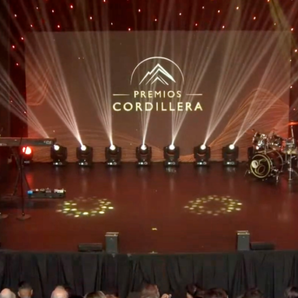 Escenario iluminado de los Premios Cordillera con el nombre del evento proyectado en una pantalla central.