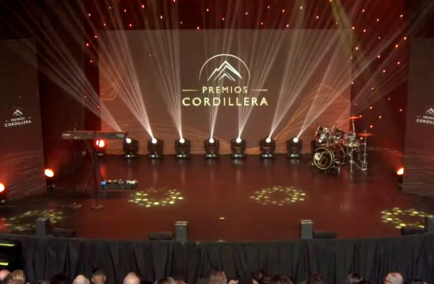 Escenario iluminado de los Premios Cordillera con el nombre del evento proyectado en una pantalla central.