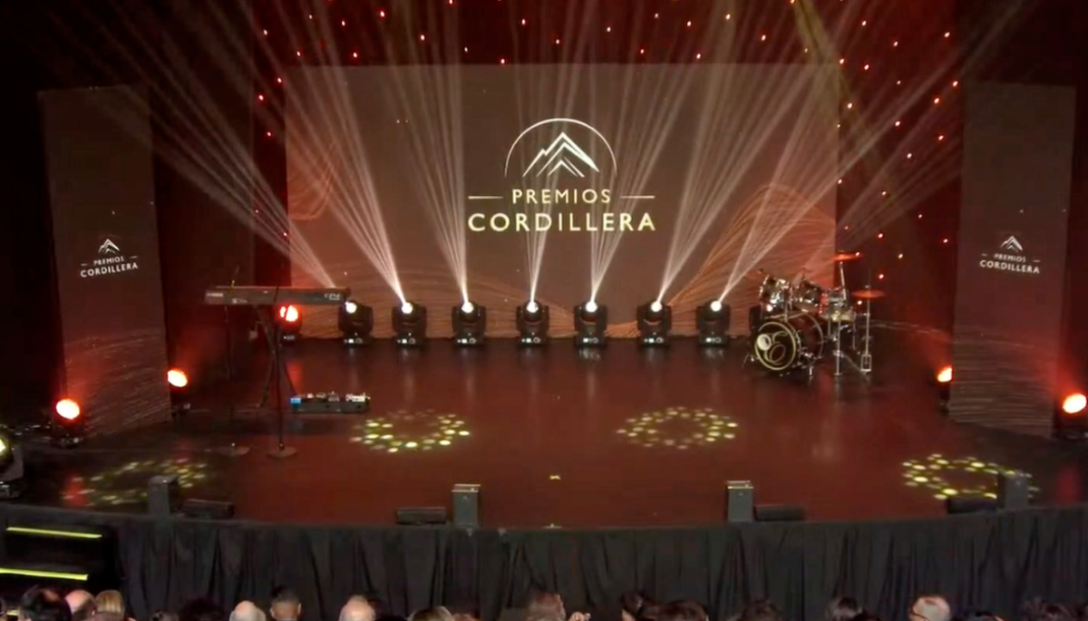 Escenario iluminado de los Premios Cordillera con el nombre del evento proyectado en una pantalla central.