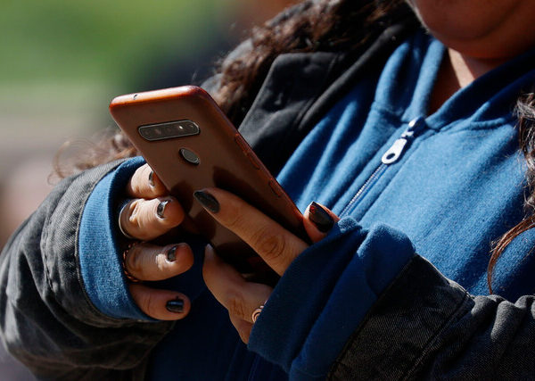 Joven utiliza un teléfono celular con ambas manos.