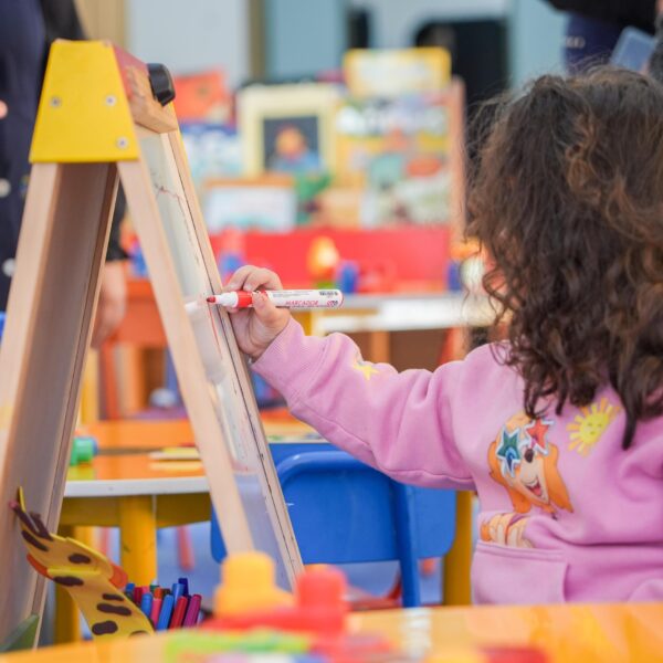 Niña dibuja en una pizarra durante una actividad infantil.