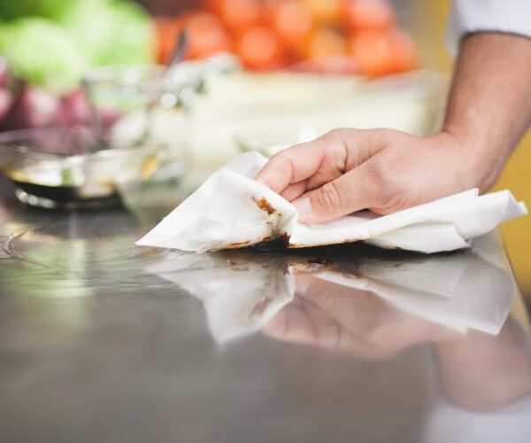 Mano limpia un mesón de cocina con un paño.