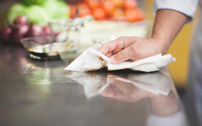 Mano limpia un mesón de cocina con un paño.
