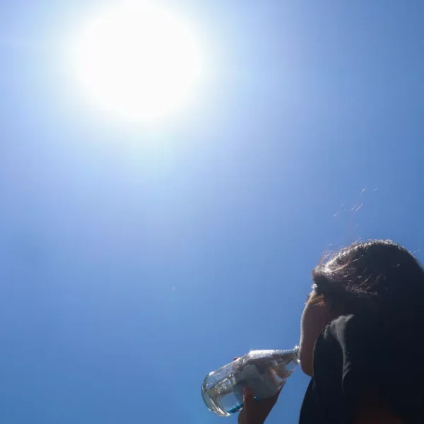 Mujer bebe agua bajo el sol en un día de altas temperaturas.