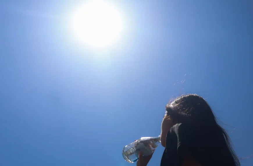 Mujer bebe agua bajo el sol en un día de altas temperaturas.
