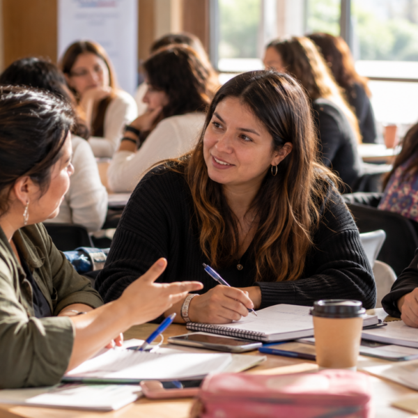 Mujeres emprendedoras conversan y toman apuntes durante una jornada de capacitación.