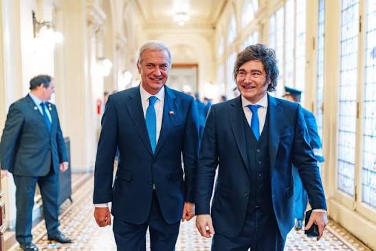 José Antonio Kast y Javier Milei caminan juntos por un pasillo.