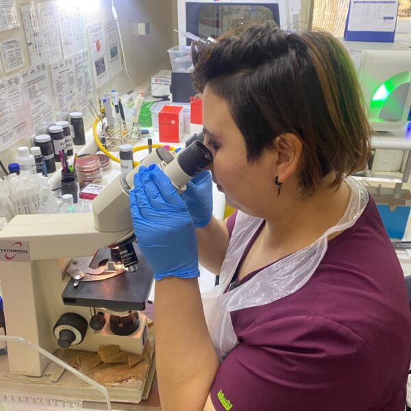 Tecnóloga médica analizando muestras con un microscopio en un laboratorio clínico
